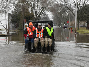 disaster response volunteers riding tractor to avoid flood waters